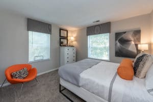 white bed in a bedroom with an orange chair
